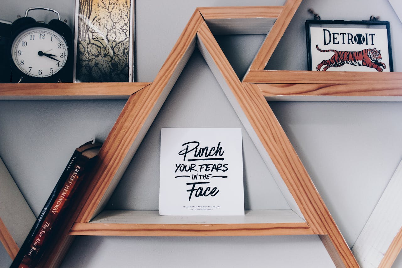 our-services-2 Triangular wooden bookshelf with motivational quote sign, clock, and decor.